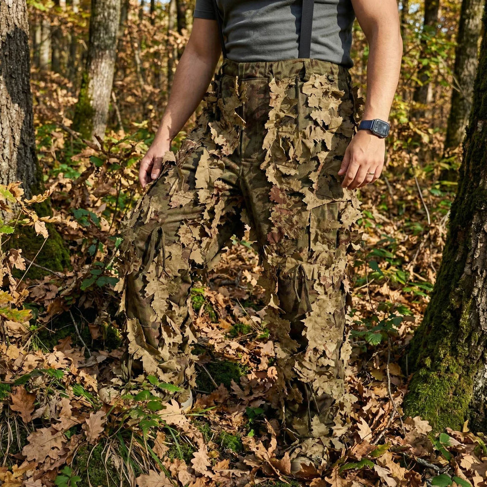 KMCS Ghillie Suit Oakland, featuring green and brown camouflage elements with a leaf-style texture for outdoor concealment.